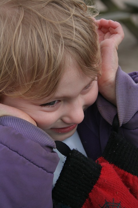 fotografia chłopca, na zdjęciu chłopiec zatyka uszy
